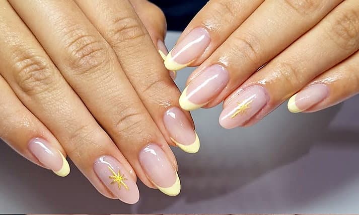 Francesinha amarela em unhas amêndoa com estrela dourada
