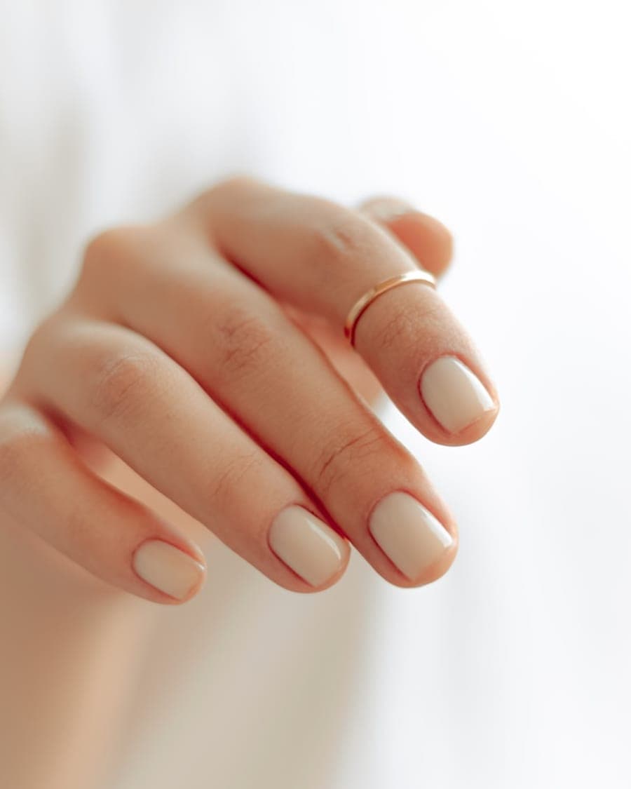 Unhas curtas nude de acabamento natural com anel dourado